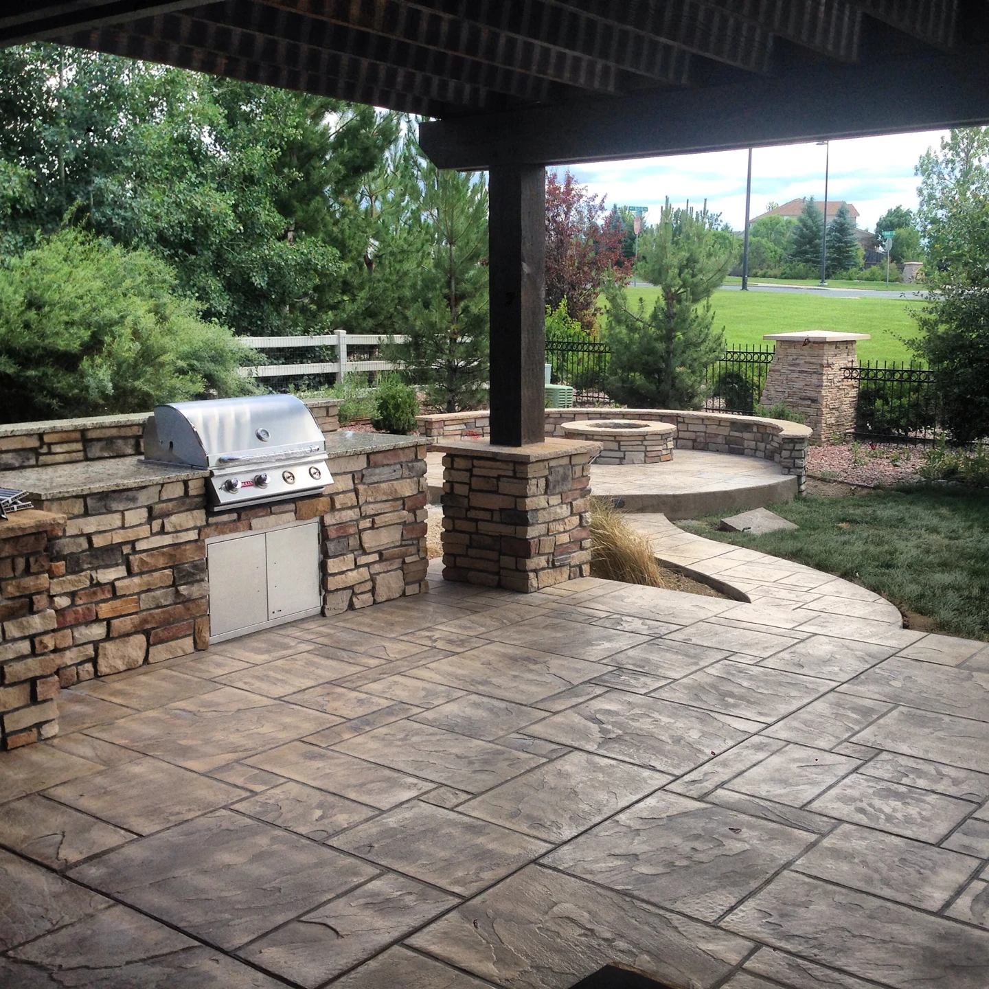 Outdoor grill and stone counter beside a paved patio